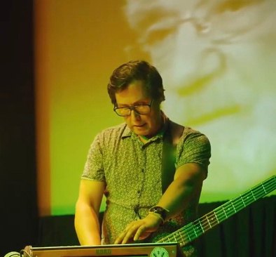 Claudio Pérez P. con guitarra, luz amarilla